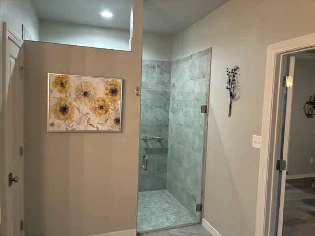 Bathroom with a tiled walk-in shower, gray walls, white trim and a framed floral print