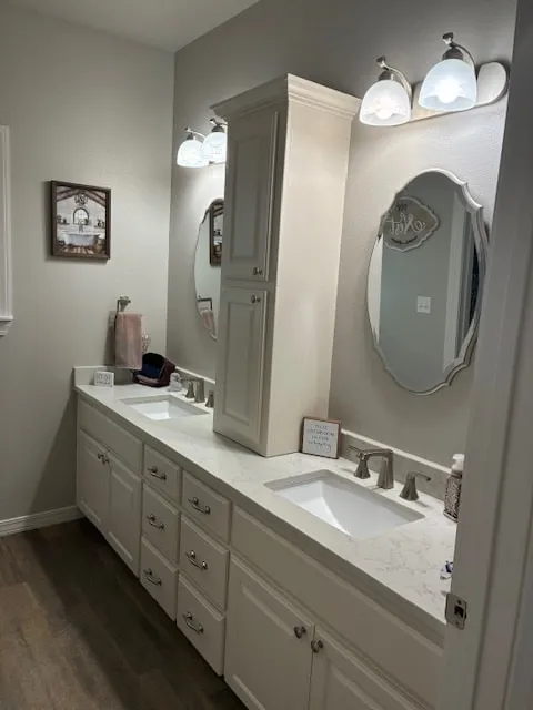 Bathroom vanity with white painted cabinet doors and drawers, gray walls and a tall linen cabinet