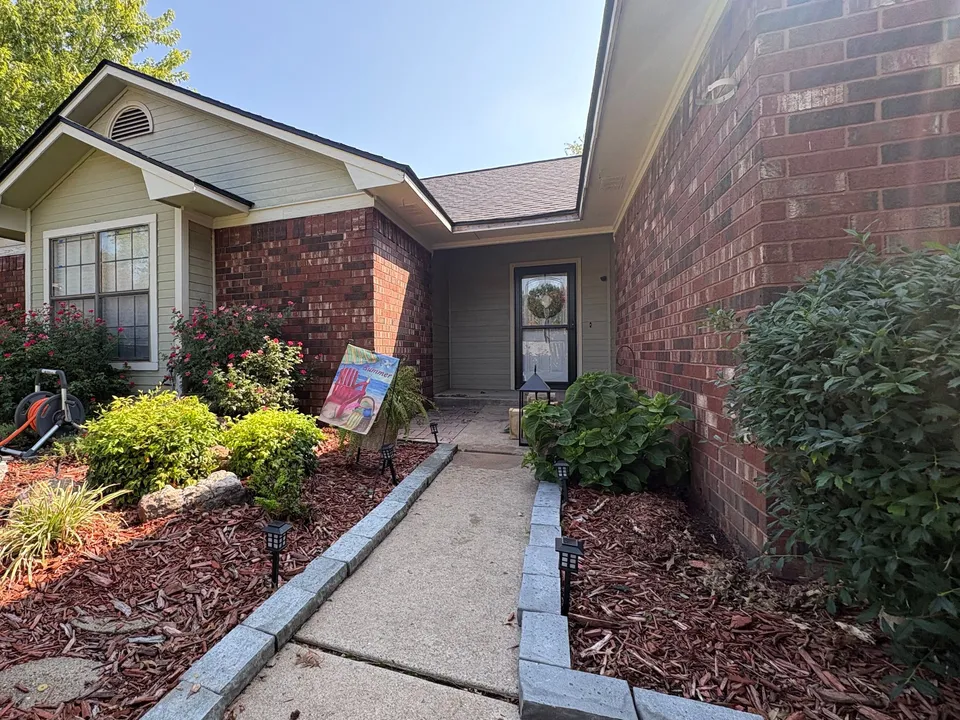 Before: the front walk of a Fort Smith house with red brick walls and pale green siding