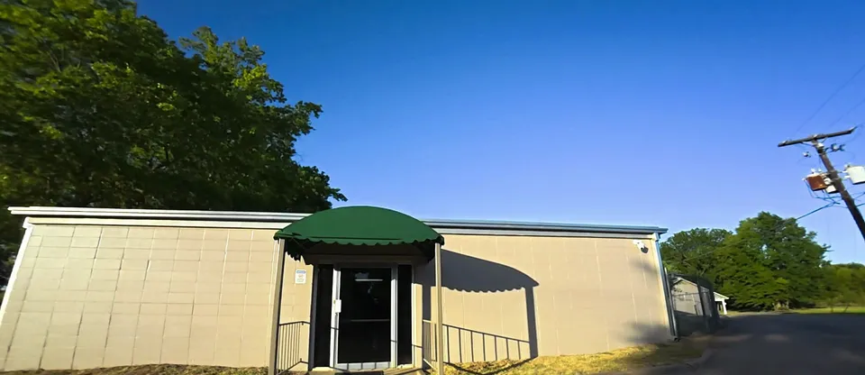 A wing of the same nursing home after painting: tan block walls and a green awning over a side door