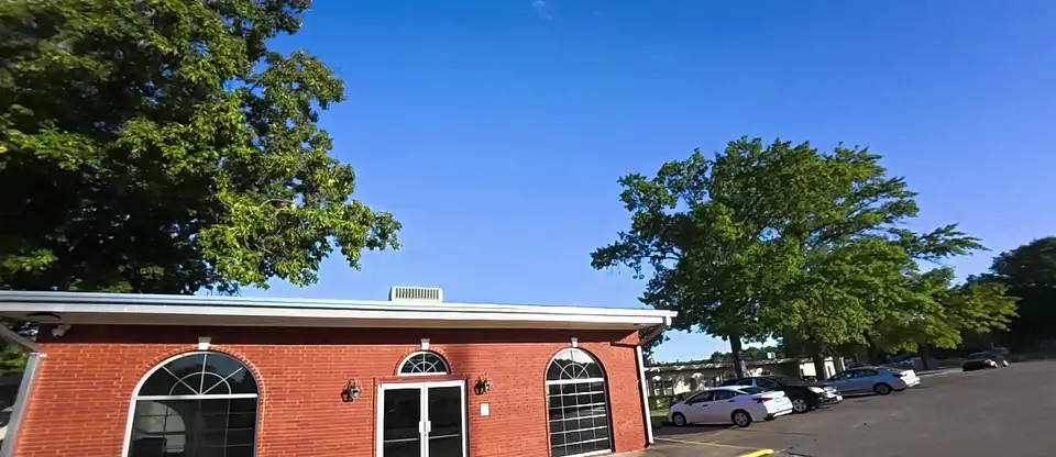 The nursing home in Greenwood after painting: a red brick entrance with 3 arched windows under white trim, seen from the parking lot