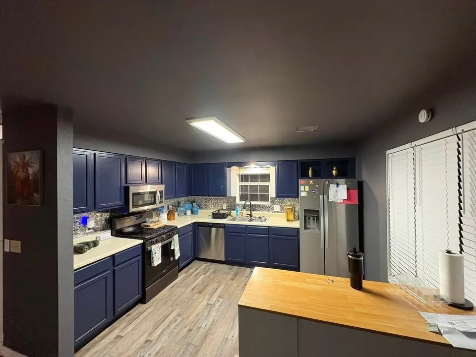 The same kitchen later, from the island: Naval Blue cabinets under a dark ceiling and dark walls