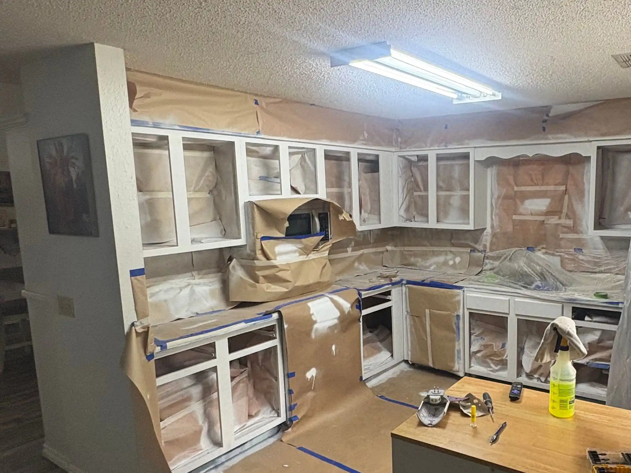 The Poteau kitchen during the job: the cabinet boxes in white primer, the counters, walls and floor covered
