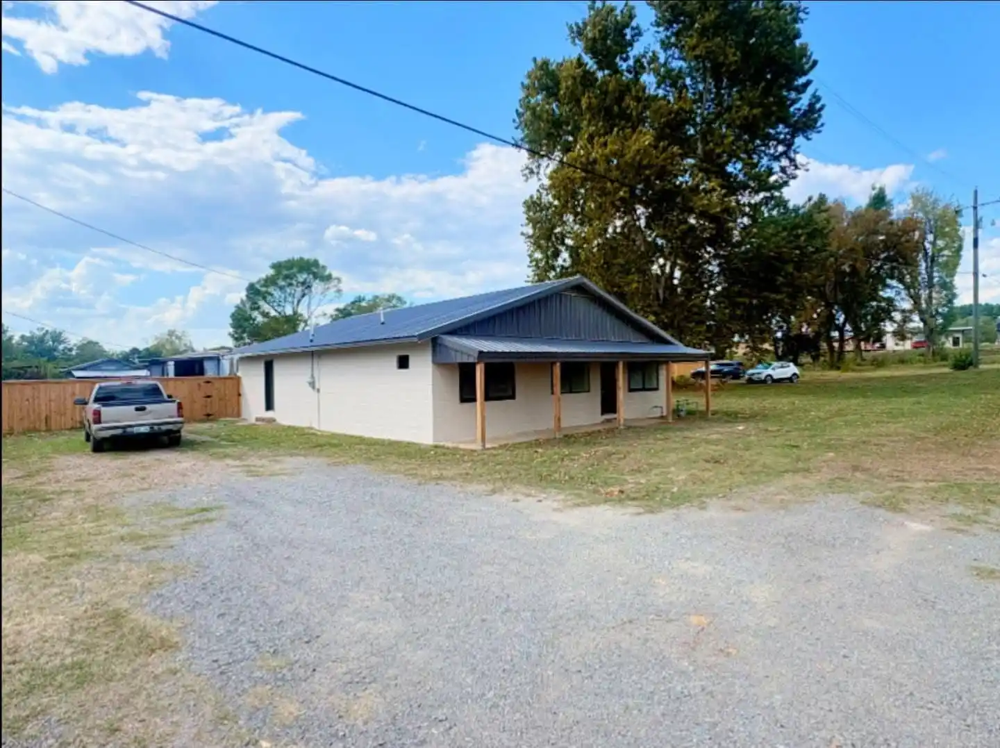 The Wister building after painting: white block walls under a dark gray gable and roof, a covered porch on wood posts